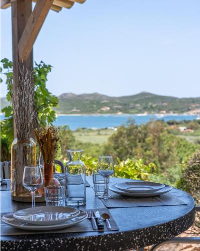 a table with plates and glasses on a table with a view at Résidence Casarina in Bonifacio
