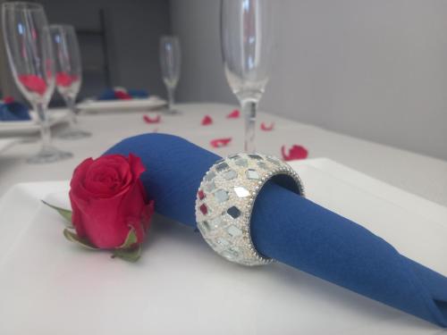 ein blaues Band und eine Rose auf einem Tisch mit Weingläsern in der Unterkunft 51 On Vlei in Kapstadt