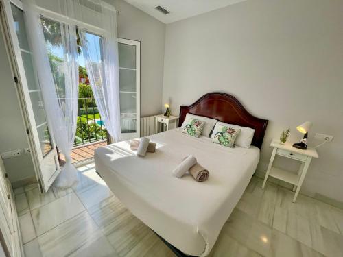 a white bedroom with a large bed and a window at GATU PREMIUM Villa Mar de Arabia in El Puerto de Santa María