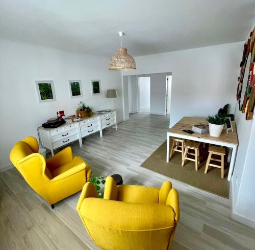 a living room with yellow chairs and a table at Galagana Charm House in Golegã