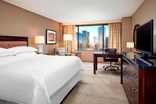 a hotel room with a bed and a desk with a television at Sheraton Centre Toronto Hotel in Toronto