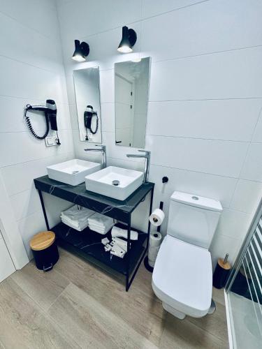 a bathroom with two sinks and a toilet and a mirror at Apartamentos Noja Playa in Noja