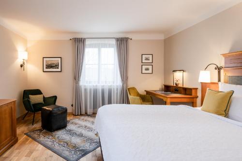 a hotel room with a bed and chairs and a window at Hotel Gut Ising in Chieming