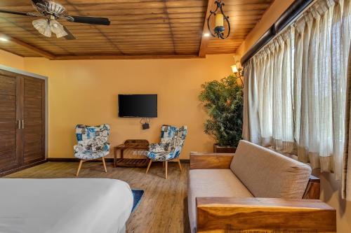 a living room with a couch and chairs and a tv at The Baga Beach Resort in Baga