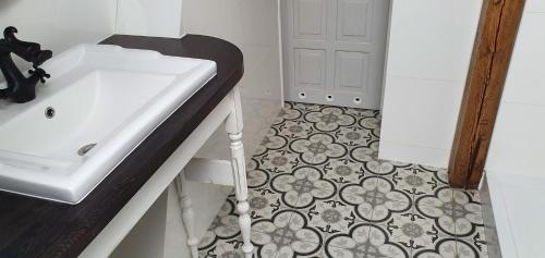 Łazienka z białą umywalką i podłogą wyłożoną kafelkami w obiekcie Millanova w mieście Milanówek