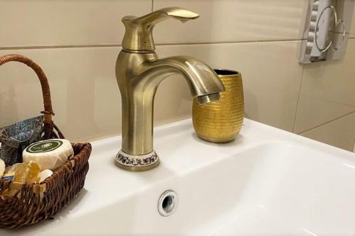 a sink with a gold faucet and a basket on it at Iris' Apartment in Thessaloniki