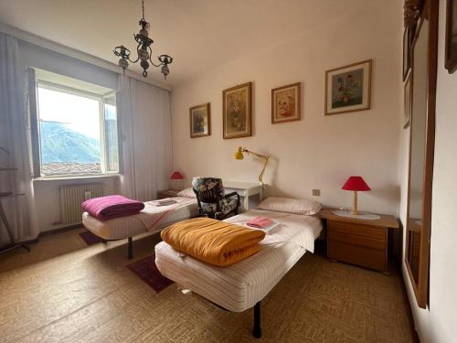 a room with two beds and a chair and a window at B&B Casa d'Arte in Levico Terme