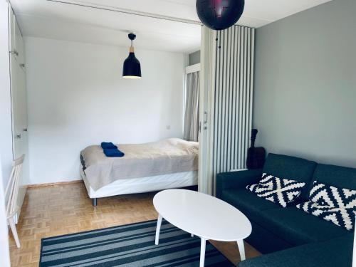 sala de estar con sofá verde y cama en Tapiola City Apartment, en Espoo