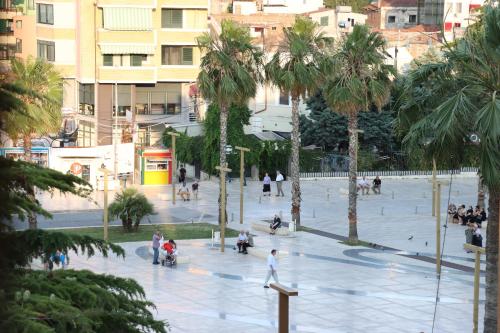 a group of people walking around a plaza with palm trees at ~Villa Gloria~ in Durrës