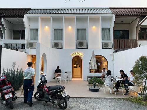 un grupo de personas sentadas fuera de un edificio en Evergreen Cafe and Hotel en Chiang Mai