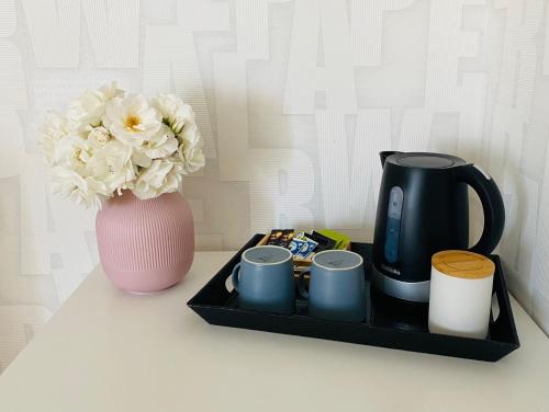 una bandeja con tazas de café y un jarrón con flores en Chez Maria, en Pontorson