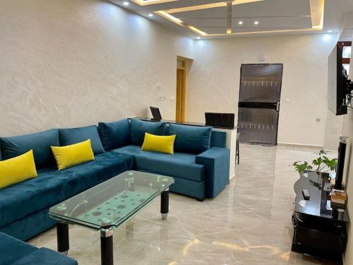 een woonkamer met een blauwe bank en gele kussens bij Appartement pour famille avec enfant in Al Hoceïma