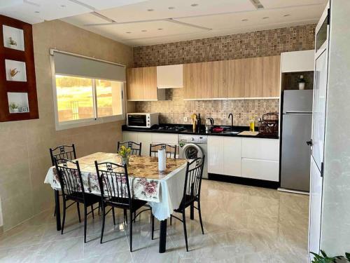 een keuken met een tafel en stoelen en een koelkast bij Appartement pour famille avec enfant in Al Hoceïma