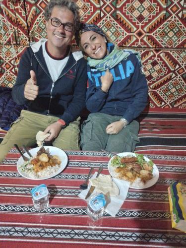 a man and woman sitting on a couch with plates of food at saleem with jeep tour in Wadi Rum