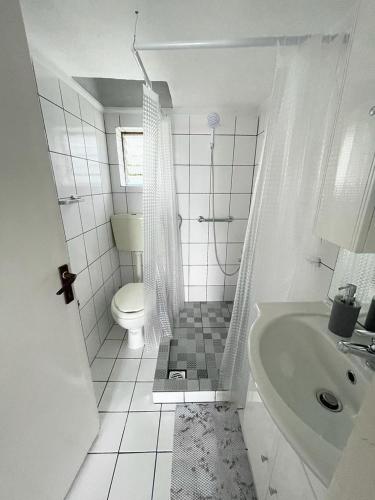 a white bathroom with a toilet and a sink at Rose House in Kavála