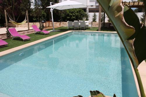 a swimming pool with pink chairs and an umbrella at Can Mossènyer in San Antonio