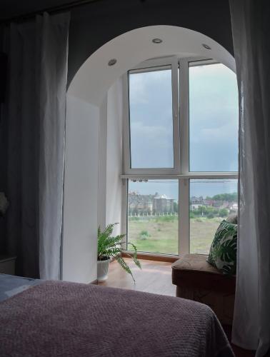a bedroom with a bed and a large window at Apartment on Parkova 36 in Chornomorsk