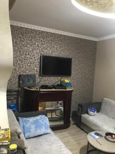 een woonkamer met een bank en een tv aan de muur bij gaydi in Gori