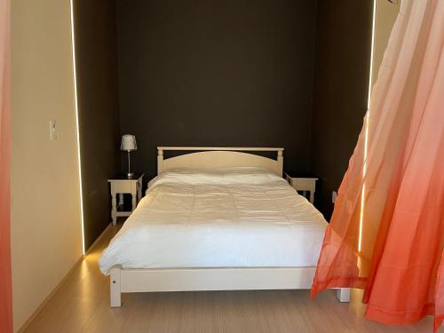 a bedroom with a white bed and two tables at Studio 402 com bela vista in Vila Velha
