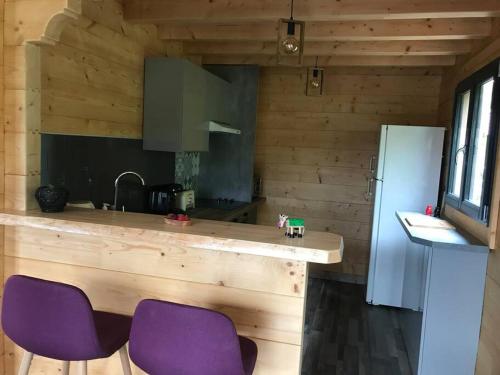 een keuken met paarse stoelen en een aanrecht met een koelkast bij Forest Jura Lodge - Chalet de la Vache in Alièze