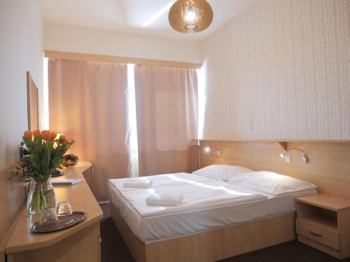 1 dormitorio con 1 cama y un jarrón de flores en Abitohotel, en Praga