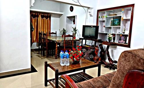 Suryas Home Stay في ديفيكولام: غرفة معيشة مع أريكة وطاولة مع زهور