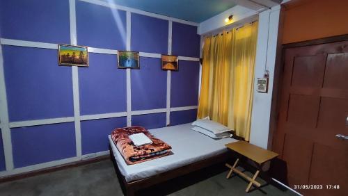 Habitación pequeña con cama y pared azul en Khowti Stay, en Dirang Dzong