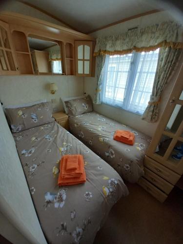 a small bedroom with two beds and a window at Cosy comfort in Ingoldmells