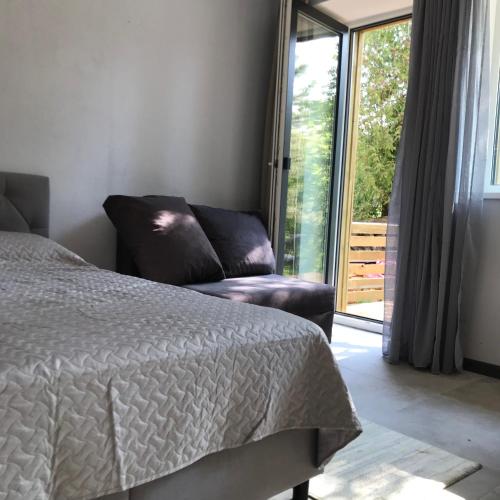a bedroom with a bed and a couch and a window at Viesu nams Baņuta1 in Saulkrasti