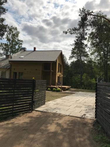 a house with a fence in front of a driveway at Viesu nams Baņuta1 in Saulkrasti