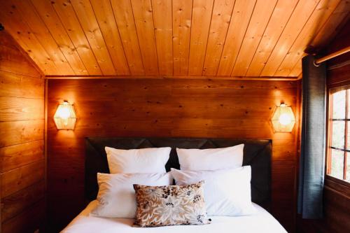 a bedroom with a bed with wooden walls and two lights at L’Hacienda Maison d’hôtes in Bagnols-en-Forêt