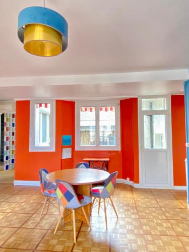 une salle à manger aux murs orange avec une table et des chaises dans l'établissement Chez Sheryl - Appartement Rouen Normandie - 271, à Rouen
