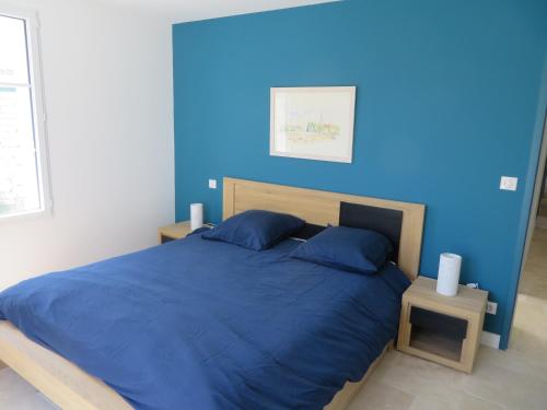 a blue bedroom with a bed with a blue wall at Le vieux chai in Sainte-Marie-de-Ré