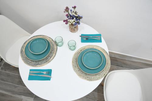 a white table with two plates and a vase of flowers at Jolie Maison in Brindisi