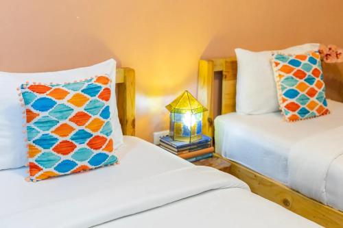 a bedroom with two beds and a lamp on a table at Rain Airport Bed and Breakfast in Manila