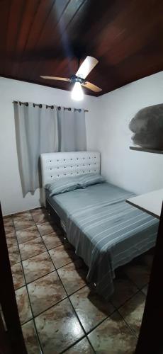 a bed in a room with a ceiling fan at Chalé do Radiola in Ilhabela