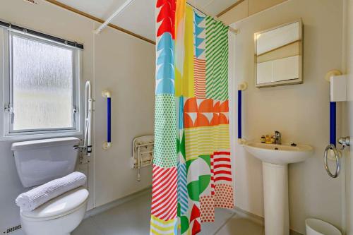 a bathroom with a shower curtain and a toilet and a sink at Sandcastle Mobility Lodge in Christchurch