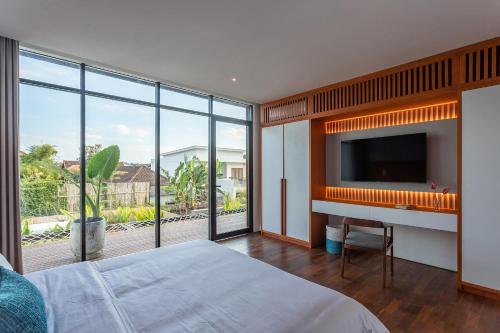 a bedroom with a tv and a large window at Aquamarine Villa 1 Canggu in Canggu