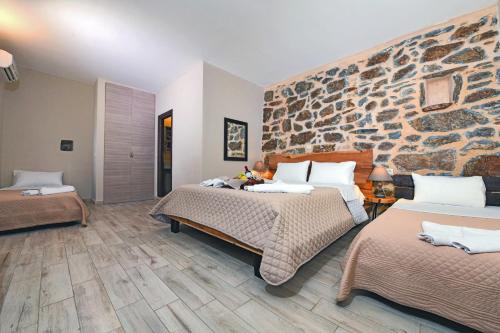 a bedroom with two beds and a stone wall at Marmari Paradise Resort Hotel in Marmari