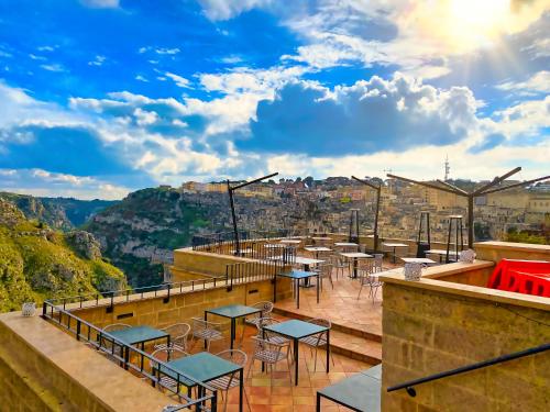 a row of tables and chairs on a patio with a view at BV Quarry Matera in Matera