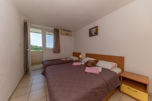 - une chambre avec 2 lits et une fenêtre dans l'établissement Apartment Knezevic, à Petrovac na Moru