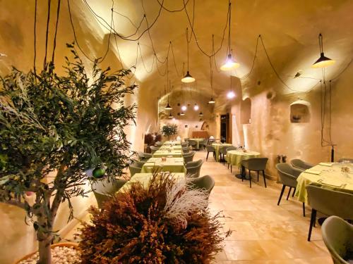 a dining room with tables and chairs and potted plants at BV Quarry Matera in Matera