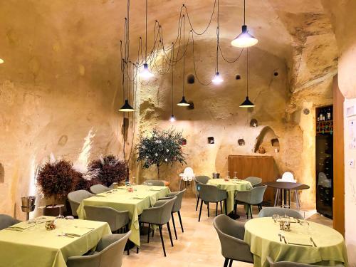 a restaurant with tables and chairs in a stone wall at BV Quarry Matera in Matera
