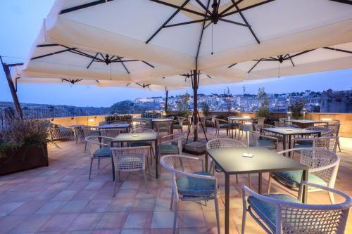 a patio with tables and chairs and umbrellas at Quarry Resort in Matera