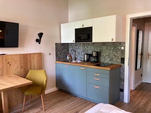 a kitchen with blue cabinets and a table and a microwave at ciao-aschau Haus zur Burg Ap112 Burgblick in Aschau