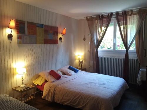 a bedroom with a white bed with two lamps and a window at Havre de paix au bords de l'Eure - divers hébergements in Neuilly