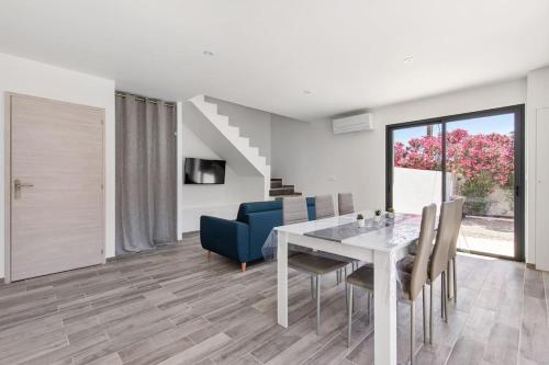 une salle à manger avec une table et des chaises blanches dans l'établissement Villa MOON - 600m plage - clim - 6 pers - Cap d'Agde, au Cap d'Agde