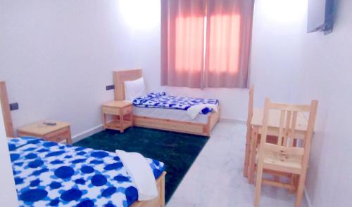 a bedroom with two beds and two chairs in it at Hotel Assafa in Dakhla