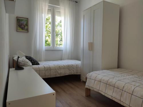 Un dormitorio con dos camas y una ventana. en Apartmani Šara 2, en Betina