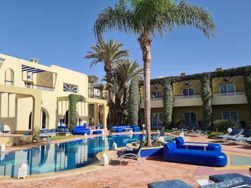 a resort pool with palm trees and blue lounge chairs at Villa Riadana in Agadir
